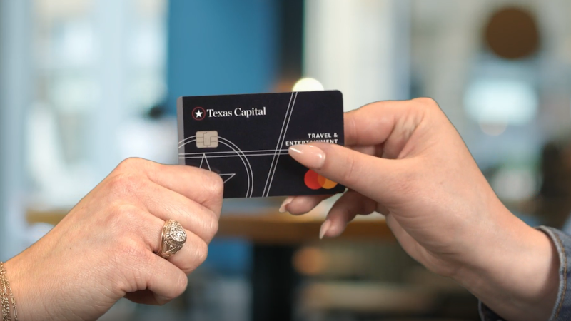 hand passing Texas Capital Travel & Entertainment card to another person's hand