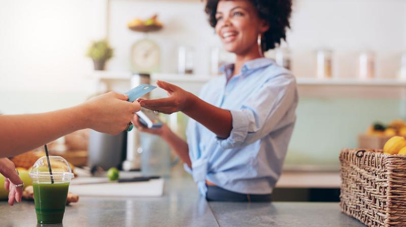 woman in blue accepting debit card from customer