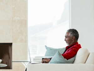 Side view of man using laptop while sitting in living room