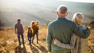 Couple with gray hair and arms around each other looking at man, children, and woman in foreground