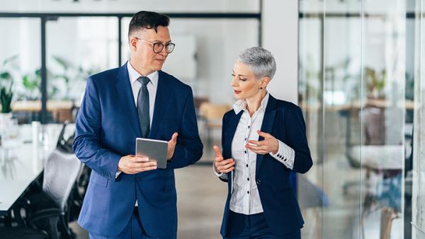Male and female professionals in business attire engaged in conversation in a modern office setting