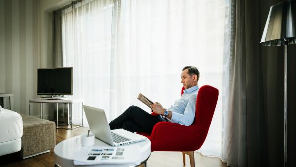 Businessman relaxing with newspaper in a modern, stylish hotel room.